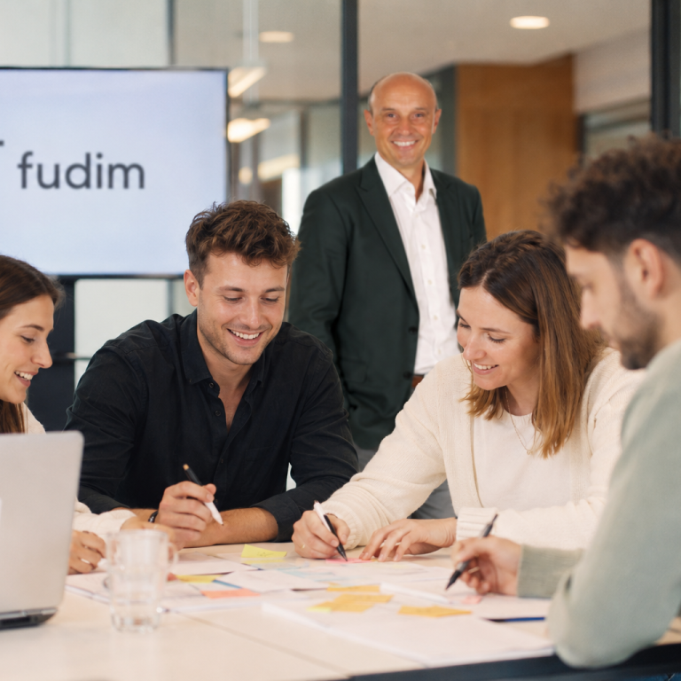 Gründungscoaching Papier mit der Aufschrift "Marketingstrategie", umgeben von Bürobedarf und einer Pflanze.